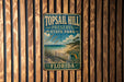A vintage metal sign for Topsail Hill Preserve State Park in Florida, featuring a beach scene and palm trees.