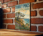 A vintage metal sign for Torrey Pines State Natural Reserve in California, featuring a scenic landscape with a pine tree and ocean.