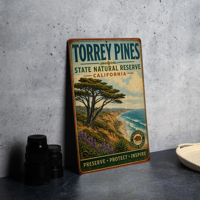 A vintage-style metal sign for Torrey Pines State Natural Reserve in California, featuring a scenic landscape with a pine tree and ocean in the background.