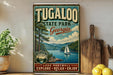 A vintage-style metal sign for Tugaloo State Park in Georgia, featuring a scenic illustration of a lake, mountains, and a sailboat.