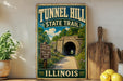 A vintage-style metal sign for Tunnel Hill State Trail in Illinois, featuring a scenic tunnel surrounded by lush greenery and a path leading through it.