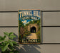A metal sign for Tunnel Hill State Trail in Illinois, featuring a scenic image of a tunnel surrounded by greenery.