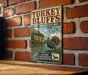 A vintage-style metal sign for the Turkey Bluffs State Fish and Wildlife Area in Illinois, featuring an illustration of a turkey and a scenic landscape.