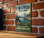 A vintage-style metal sign for Twanoh State Park, featuring a scenic landscape with mountains, trees, and a lake.