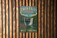 A vintage-style metal sign for Twin Falls Resort State Park in West Virginia, featuring a waterfall and forest scenery.