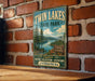 A vintage-style metal sign for Twin Lakes State Park, featuring a scenic landscape with pine trees, a lake, and mountains.