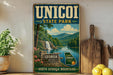 A vintage-style sign for "Unicoi State Park" featuring a scenic landscape with a waterfall, mountains, and a river.