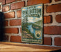 A vintage-style metal sign for Upper Pine Bottom State Park in Pennsylvania, featuring a scenic landscape with pine trees, a river, and mountains.