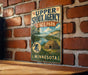 A vintage metal sign for Upper Sioux Agency State Park in Minnesota, featuring a scenic illustration of the park and a Native American teepee.