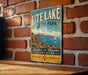 A vintage metal sign for Utah Lake State Park, featuring a scenic illustration of a lake, mountains, and a sailboat.
