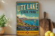 A vintage-style metal sign for Utah Lake State Park, featuring a scenic landscape with a sailboat on the lake and mountains in the background.