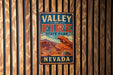 A vintage metal sign for Valley of Fire State Park in Nevada, featuring an illustration of the park's iconic rock formations.