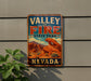 A vintage-style metal sign for Valley of Fire State Park in Nevada, featuring a desert landscape with mountains and a prominent rock formation.