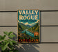 A vintage-style metal sign for Valley of the Rogue State Park, featuring a scenic mountain landscape with a river.