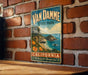 A vintage-style metal sign for Van Damme State Park in California, featuring a scenic coastal landscape with mountains, trees, and a body of water.