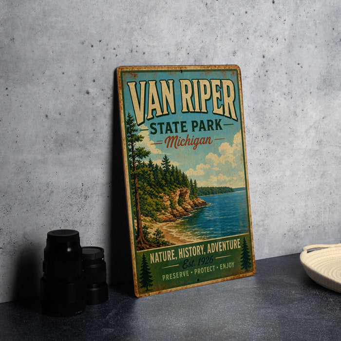 A vintage-style sign for Van Riper State Park in Michigan, featuring a scenic landscape with a lake and forest.