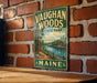 A vintage metal sign for Vaughan Woods State Park in Maine, featuring a scenic landscape with a river and forest.
