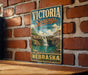 A vintage-style metal sign for Victoria Springs, a state recreation area in Nebraska, is displayed on a brick wall.