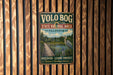 A vintage metal sign for Volo Bog State Natural Area in Illinois, featuring a scenic illustration of a wooden boardwalk leading to a pond with a heron.