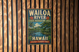 A vintage-style metal sign for the Waioa River State Recreation Area in Hawaii, featuring a tropical landscape with palm trees, mountains, and a river.