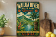 A vintage-style poster advertising Wailua River State Park in Hawaii, featuring a tropical landscape with a tiki statue, palm trees, and a river.