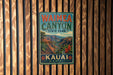 A vintage-style metal sign for Waimea Canyon State Park in Kauai, Hawaii, featuring a scenic mountain landscape and tropical vegetation.
