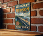 A vintage-style metal sign for "WALKWAY OVER THE HUDSON STATE HISTORIC PARK" is displayed on a brick wall, with a wooden table below it.