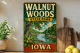 A vintage-style sign for Walnut Woods State Park in Iowa, featuring a scenic illustration of a waterfall and lush greenery.