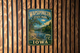 A vintage metal sign for Wapsipinicon State Park in Iowa, featuring a scenic landscape with a river and bridge.
