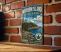 A vintage-style metal sign for Warren Island State Park in Maine, featuring a scenic landscape with pine trees, a rocky coastline, and a body of water.