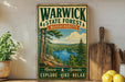 A vintage-style metal sign for Warwick State Forest in Massachusetts, featuring a scenic landscape with pine trees, a lake, and mountains.