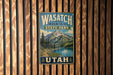 A vintage metal sign for Wasatch Mountain State Park in Utah, featuring a scenic mountain landscape with a lake and pine trees.