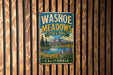 A vintage metal sign for Washoe Meadows State Park in California, featuring a scenic landscape with a lake, mountains, and wildflowers.