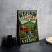 A vintage-style sign for Waterbury Center State Park in Vermont, featuring a red wooden bridge and a scenic mountain landscape.