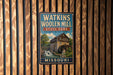 A vintage metal sign for Watkins Woolen Mill, a historic site in Missouri, featuring an illustration of the mill and a waterfall.