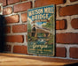 A vintage-style metal sign for Watson Mill Bridge, a historic bridge in Georgia, is displayed on a brick wall.