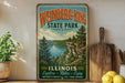 A vintage-style sign for Weinberg-King State Park in Illinois, featuring a scenic landscape with a lake and mountains.