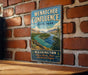 A vintage-style metal sign for Wenatchee Confluence State Park, featuring a scenic landscape with a river and mountains.