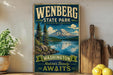 A vintage-style sign for Wenberg State Park, featuring a scenic mountain landscape with pine trees and a lake, along with the text "Wenberg State Park Washington Nature's Beauty Awaits".