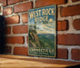 A vintage-style sign for West Rock Ridge State Park in Connecticut, featuring a scenic landscape with a mountain and a river.