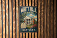 A vintage-style metal sign for White Hall, a historic house in Kentucky, is displayed on a wooden wall.