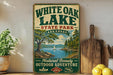 A vintage-style sign for White Oak Lake State Park in Arkansas, featuring a scenic illustration of a lake surrounded by trees and mountains.