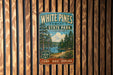 A vintage-style metal sign for White Pines Forest State Park in Illinois, featuring a scenic illustration of pine trees and a lake.