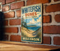 A vintage-style sign for Whitefish Dunes State Park in Wisconsin, featuring a scenic landscape with a beach, dunes, and a lake.
