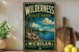 A vintage-style metal sign for Wilderness State Park in Michigan, featuring a scenic landscape with pine trees, a lake, and mountains.