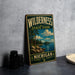 A vintage-style metal sign for Wilderness State Park in Michigan, featuring a scenic landscape with pine trees, a lake, and mountains.