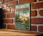 A vintage-style metal sign for Willamette Mission State Park in Oregon, featuring a scenic illustration of a church and a river.
