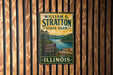 A vintage-style metal sign for William G. Stratton State Park in Illinois, featuring a scenic image of the park and its surroundings.