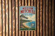 A vintage metal sign for William Mitchell State Park in Michigan, featuring a scenic landscape with a pine tree, a beach, and a lake.