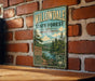 A vintage-style metal sign for the Willowdale State Forest in Massachusetts, featuring a scenic image of a forest and a river.